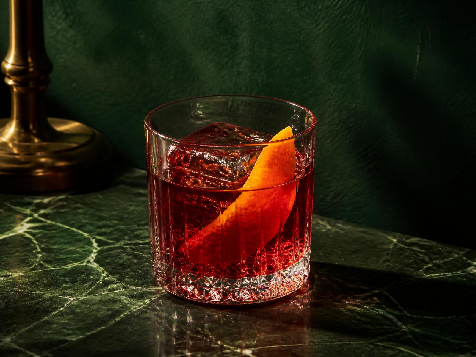 A classic Negroni served over a single large ice cube with an orange peel